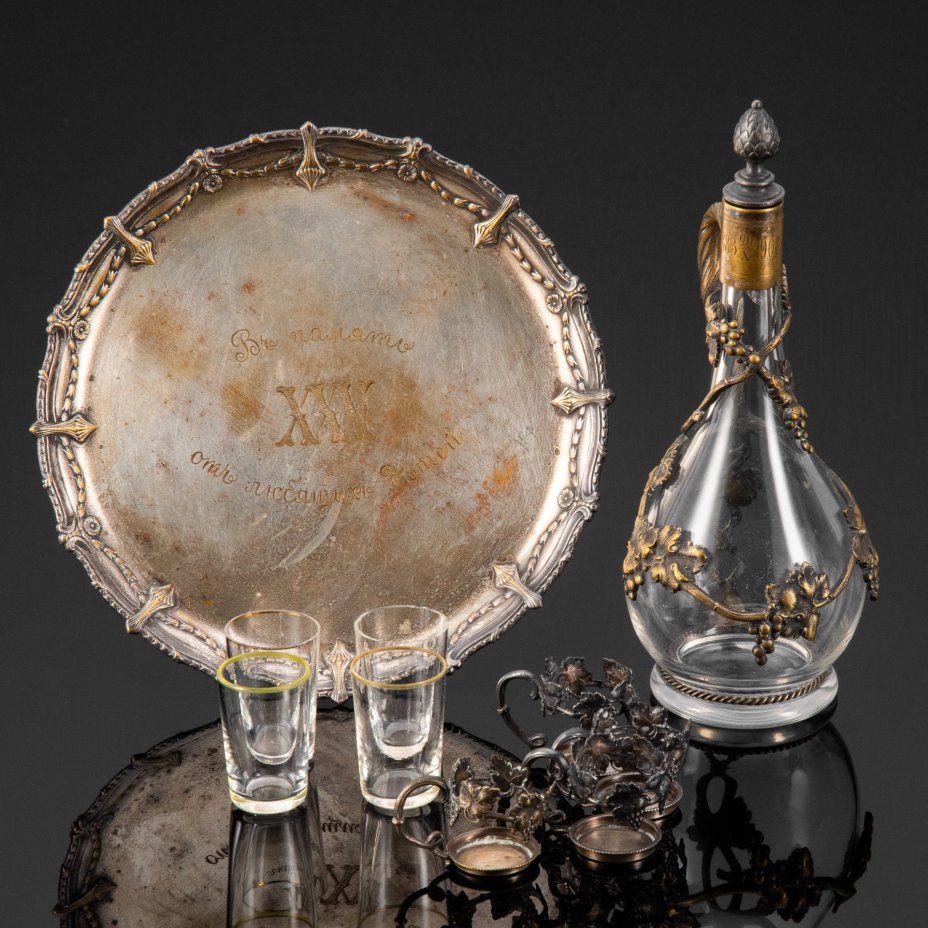 Набор для крепких напитков, состоящий из подноса, графина и четырех стопок на подставках, с растительным декором и дарственной надписью "Въ память отъ любящихъ дѣтей XXV" и "1883.20.10/1908", стекло, металл, серебрение, Plewkiewicz & Co. (Фабрика Романа Плевкевича), Царство Польское, 1908 г.