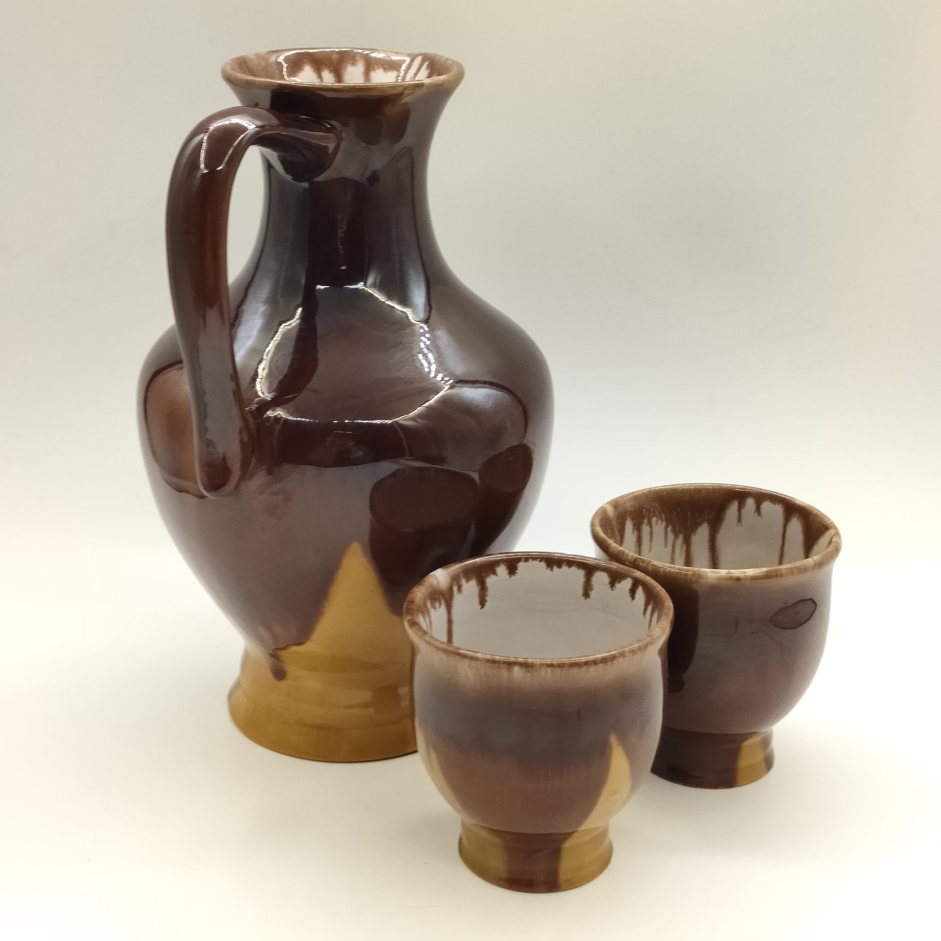 Кувшин с двумя стаканами и ложечкой жёлто-коричневого оттенка
