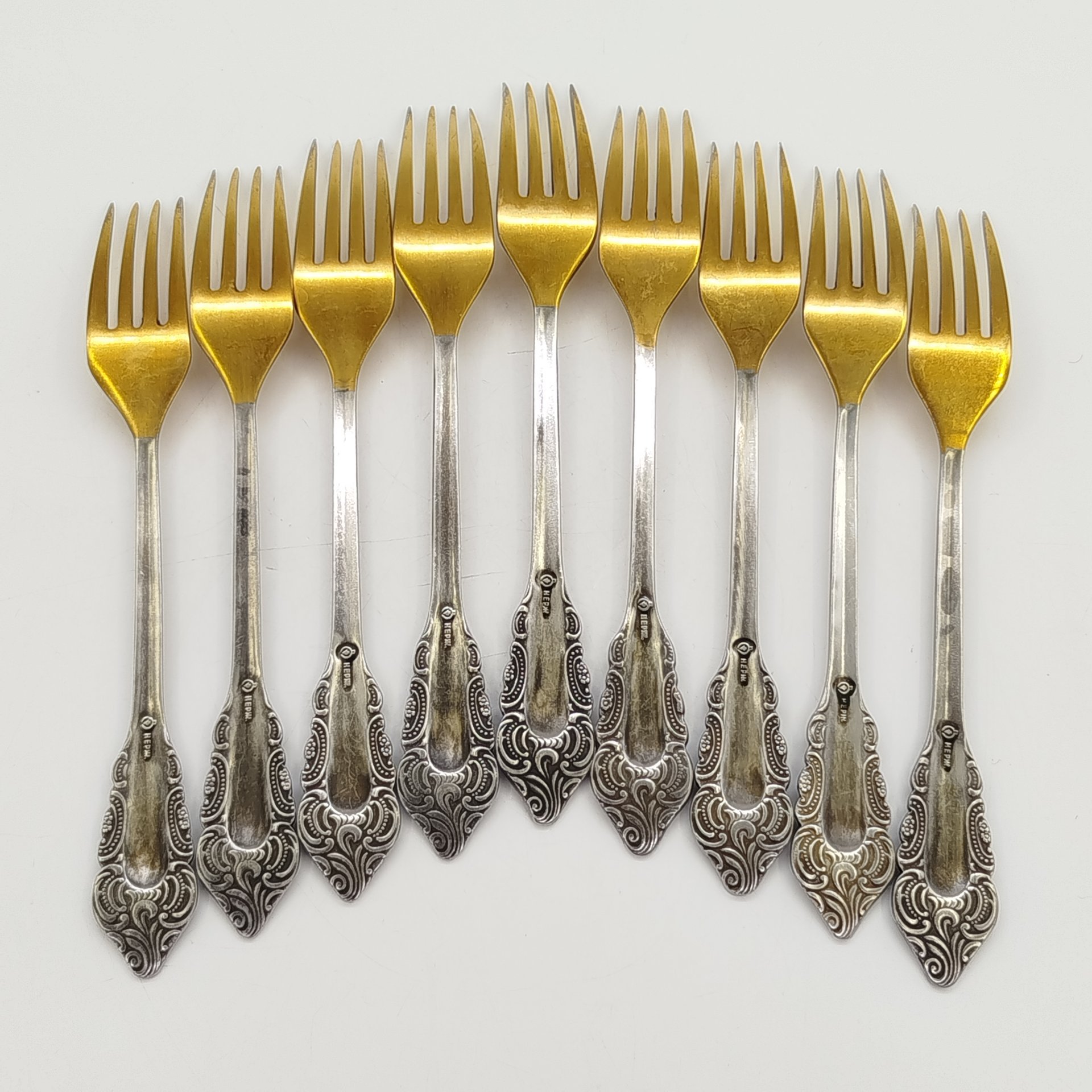Набор из 9-ти столовых вилок, украшенных растительным декором, нержавеющая сталь, золочение, Павловский завод художественных металлоизделий им. С.М. Кирова, СССР