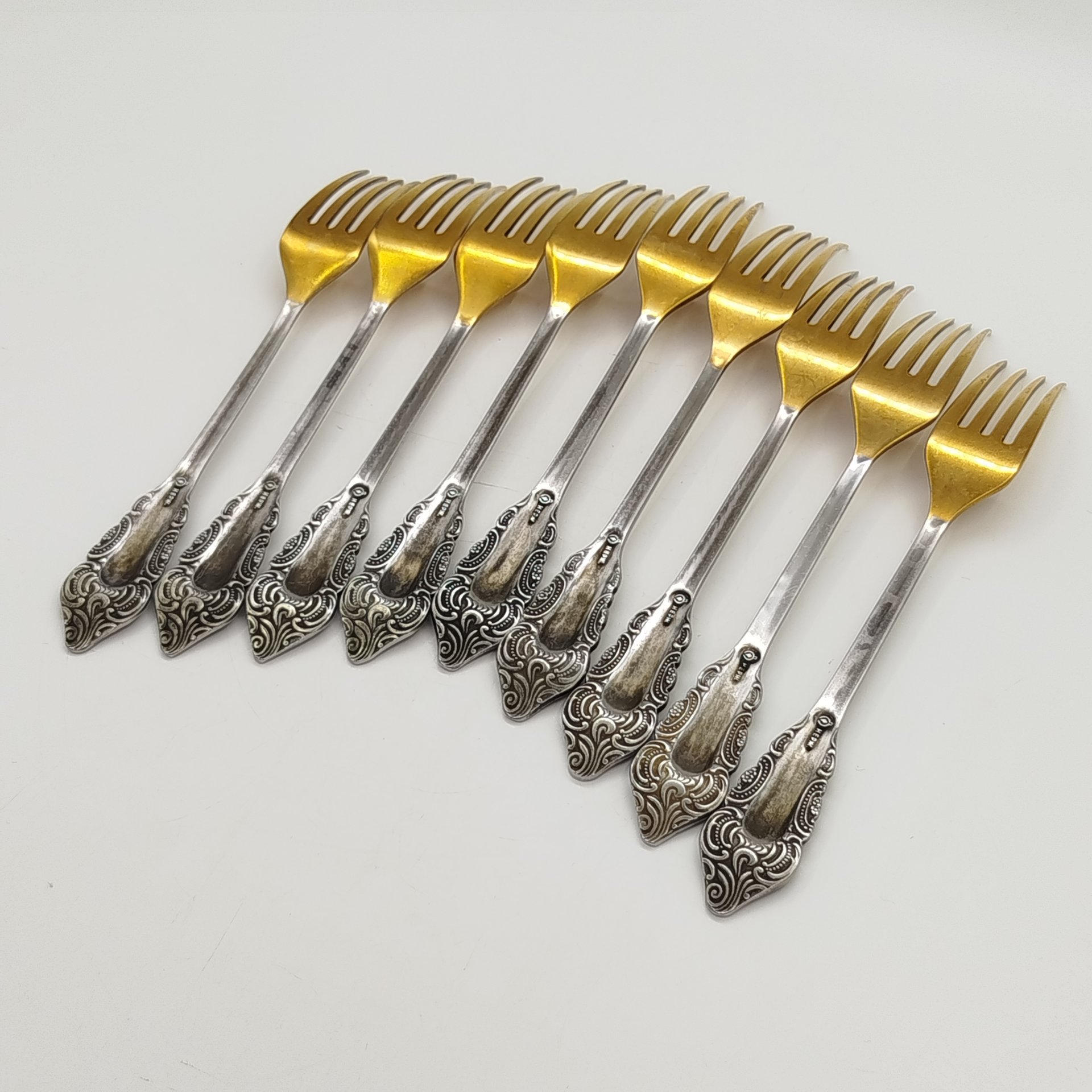 Набор из 9-ти столовых вилок, украшенных растительным декором, нержавеющая сталь, золочение, Павловский завод художественных металлоизделий им. С.М. Кирова, СССР