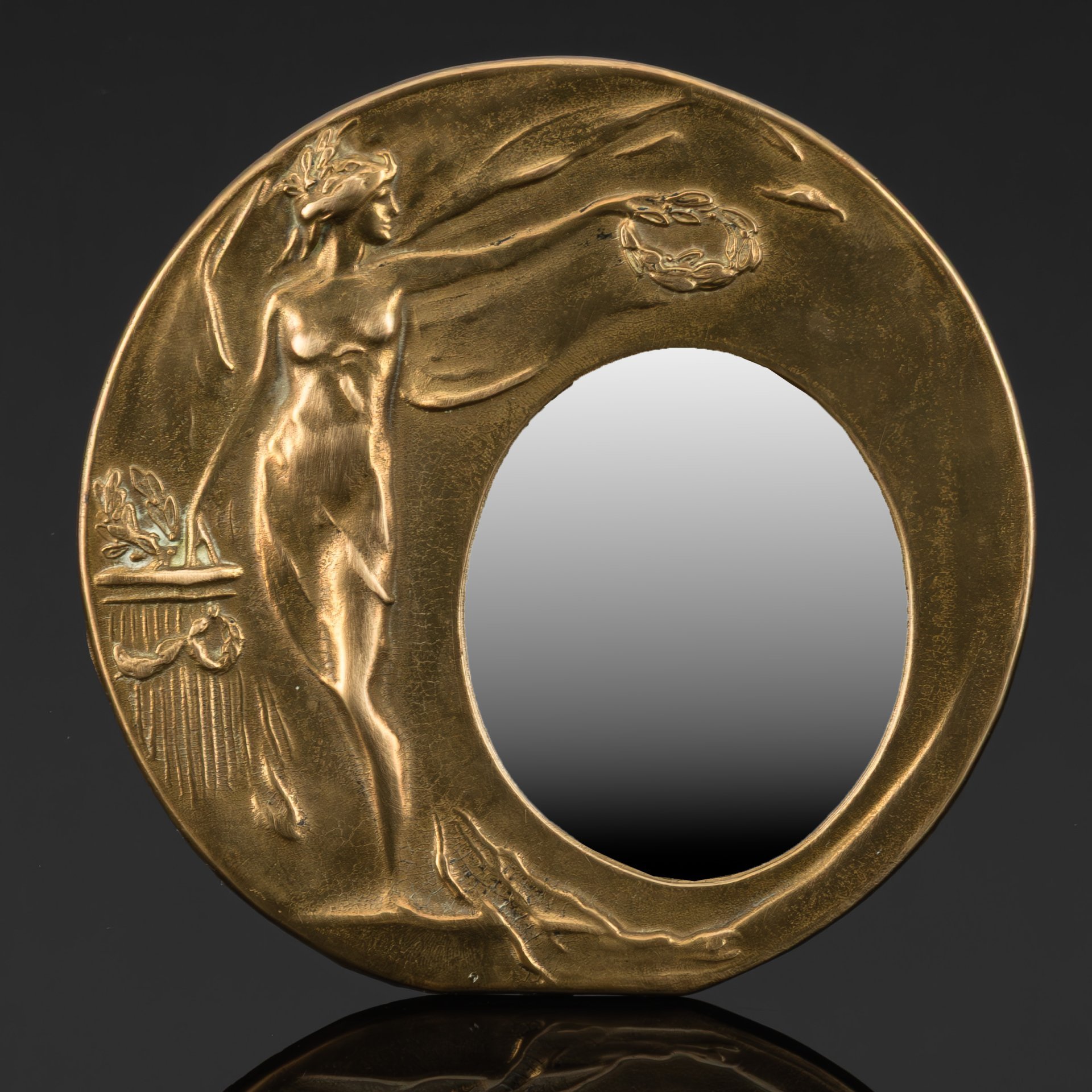 Зеркало настольное округлой формы в стиле модерн, декорированное рельефным изображением девушки с лавровым венком в руках