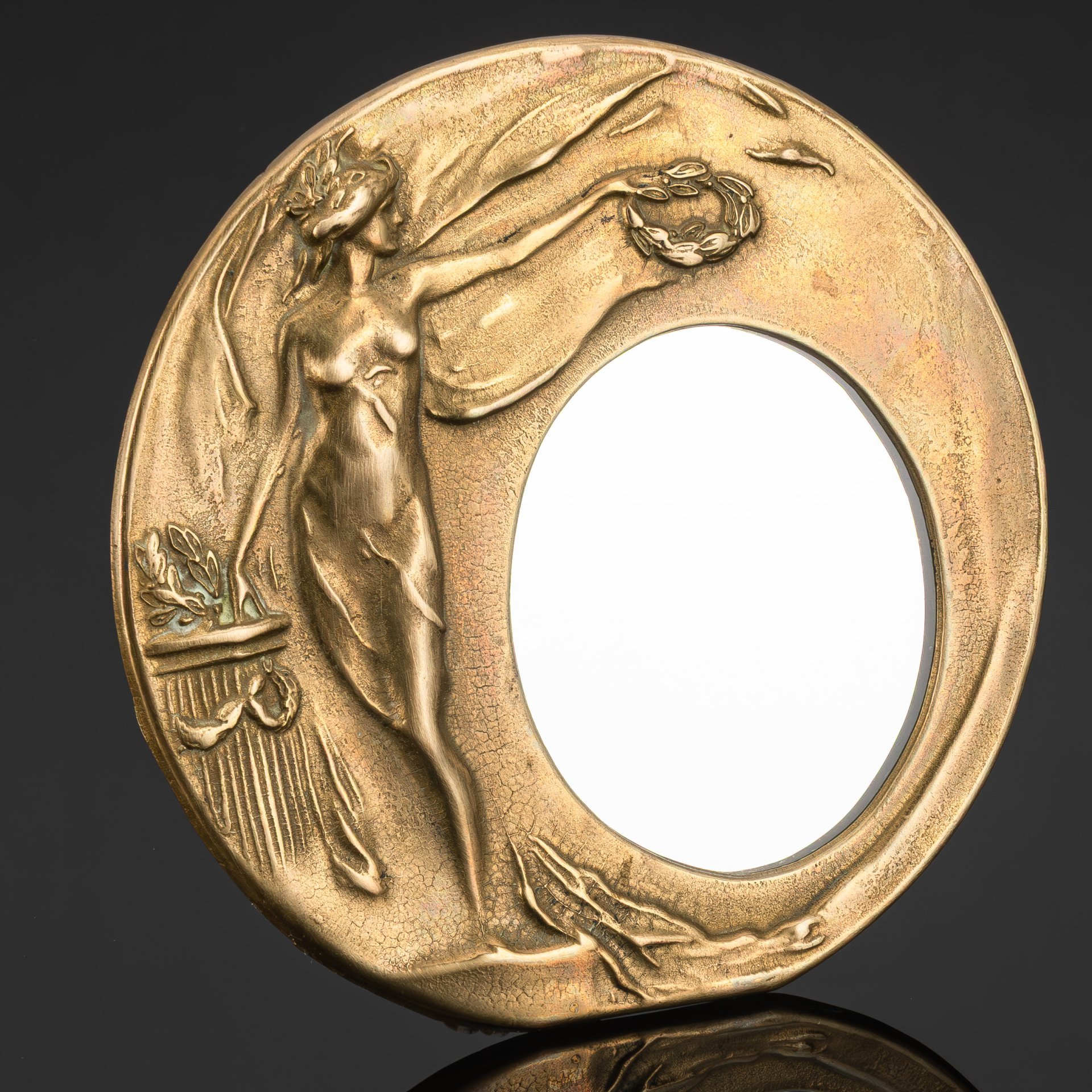 Зеркало настольное округлой формы в стиле модерн, декорированное рельефным изображением девушки с лавровым венком в руках