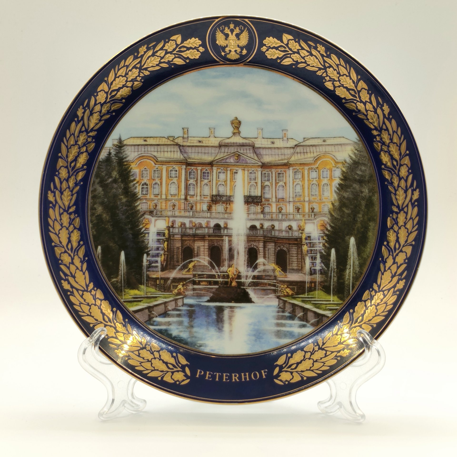 Тарелка настенная "Большой каскад и Большой дворец. Петергоф" из коллекционной серии "Лучшие виды Петергофа", АКМ Сувениры, фарфор, крытье кобальтом, деколь, золочение, Российская Федерация, 2000-2020 гг.
