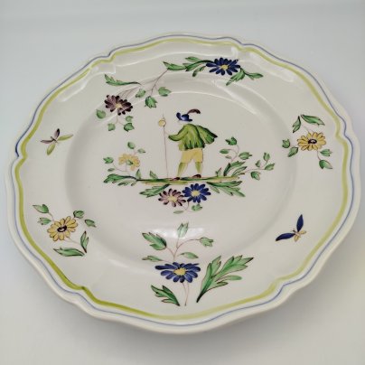 Тарелка обеденная, украшенная изображением цветов, бабочек и деревенского персонажа, узор "Moustiers", мануфактура "Longchamp", фаянс, деколь с подрисовкой, Франция, 1950-1970 гг.