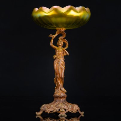 Фруктовница (ваза) в стиле модерн на фигурном основании в виде нимфы на шаре, которая держит чашу зеленоватого оттенка в виде раскрывающейся водяной лилии, loetz (?), металл, литье, формовка, стекло, гутная техника, иризация, Западная Европа, 1900-1920 гг.