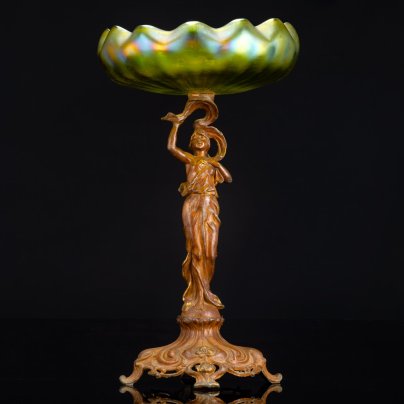 Фруктовница (ваза) в стиле модерн на фигурном основании в виде нимфы на шаре, которая держит чашу зеленоватого оттенка в виде раскрывающейся водяной лилии, loetz (?), металл, литье, формовка, стекло, гутная техника, иризация, Западная Европа, 1900-1920 гг.