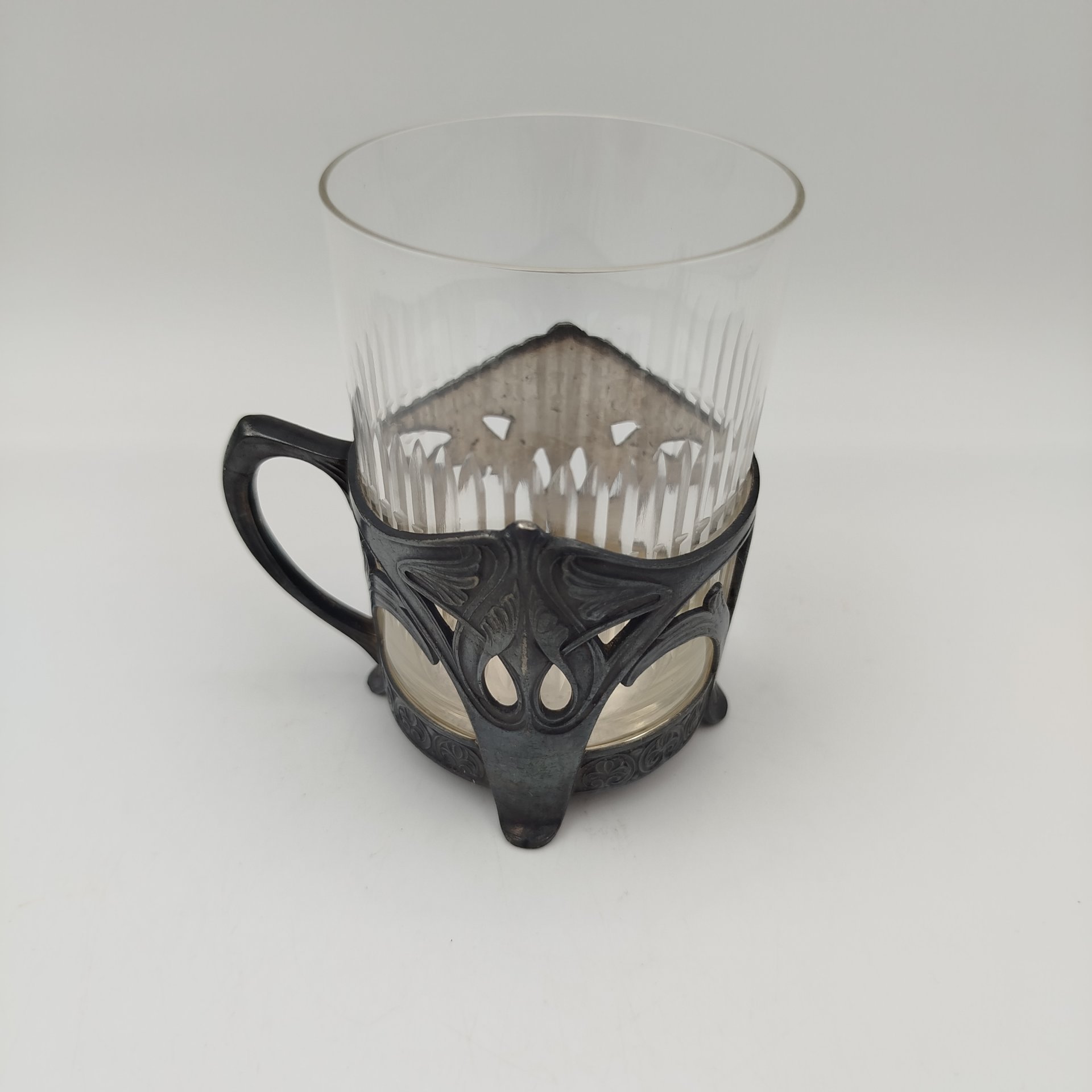 Подстаканник в стиле модерн с прорезным туловом и растительным декором (в комплекте со стаканом с геометрическим декором), металл, серебрение, стекло, Plewkiewicz & Co. (Фабрика Романа Плевкевича), Царство Польское, 1886-1914 гг.