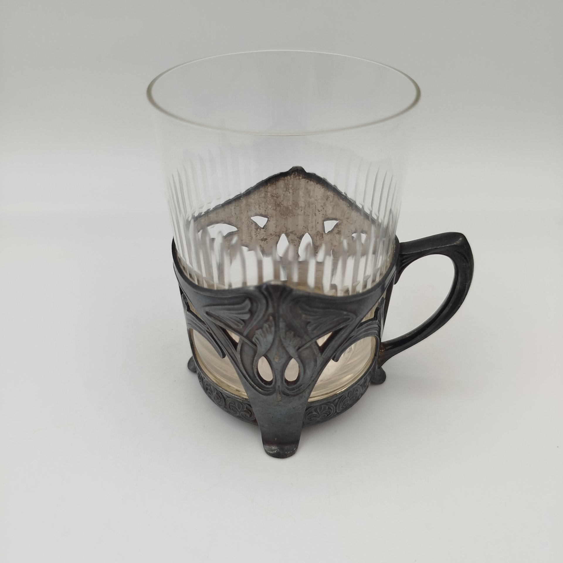 Подстаканник в стиле модерн с прорезным туловом и растительным декором (в комплекте со стаканом с геометрическим декором), металл, серебрение, стекло, Plewkiewicz & Co. (Фабрика Романа Плевкевича), Царство Польское, 1886-1914 гг.