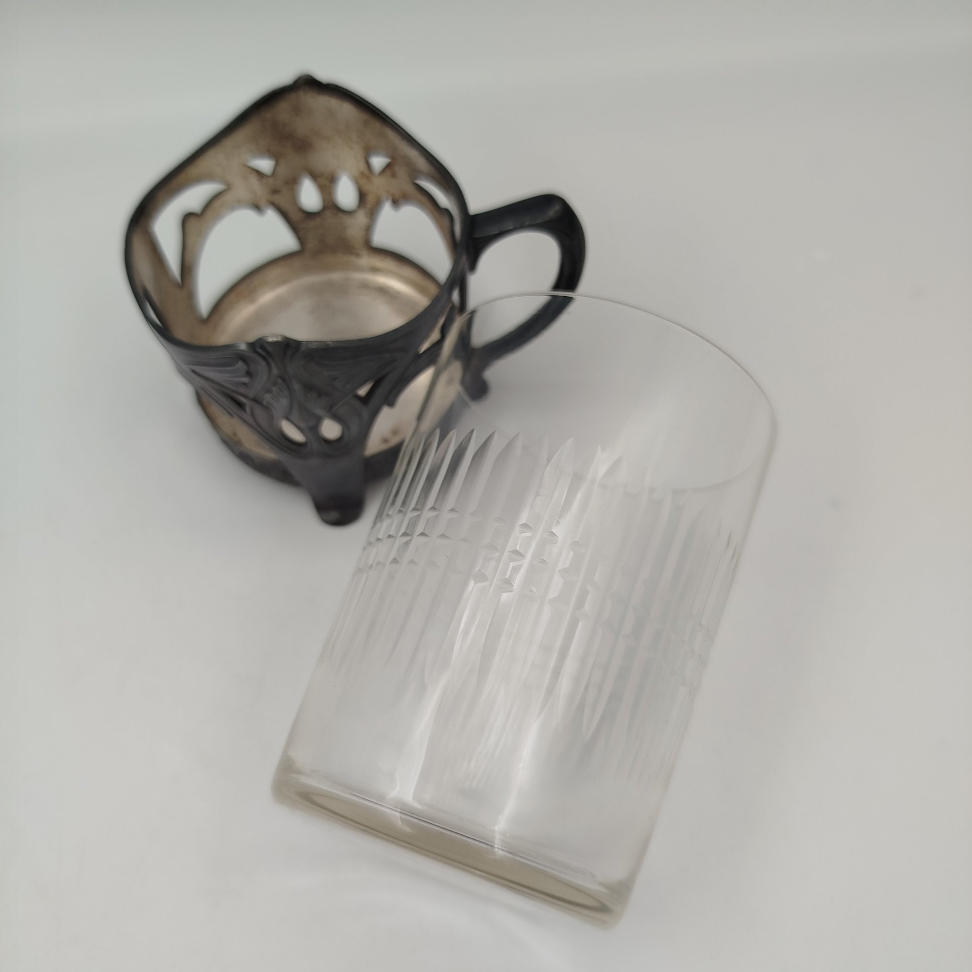 Подстаканник в стиле модерн с прорезным туловом и растительным декором (в комплекте со стаканом с геометрическим декором), металл, серебрение, стекло, Plewkiewicz & Co. (Фабрика Романа Плевкевича), Царство Польское, 1886-1914 гг.