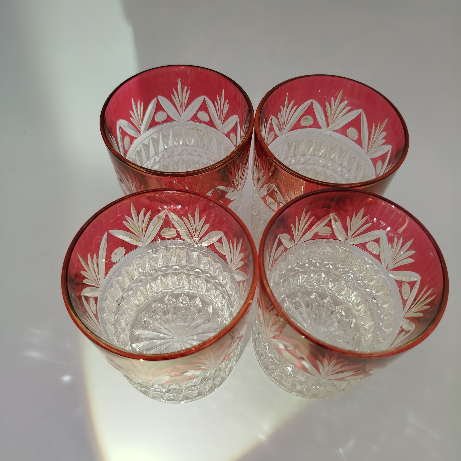 Набор из четырех стаканов с рельефным декором и верхней частью малинового оттенка с растительным орнаментом, стекло, нацвет, СССР, 1950-1980 гг.