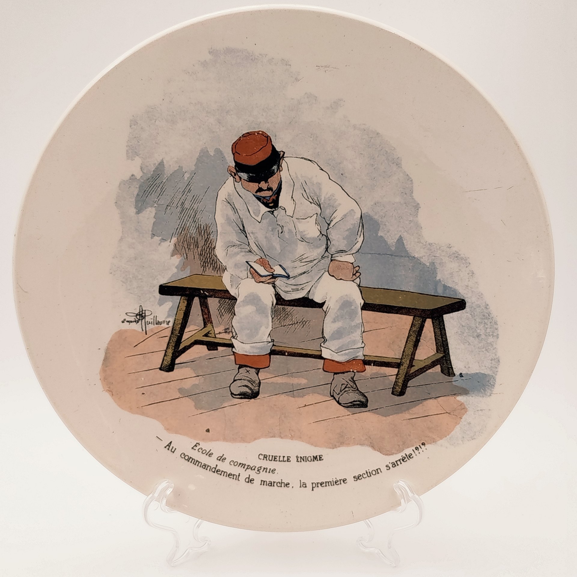 Тарелка декоративная "Cruelle Enigme. Ecole de compagnie.  Au commandement de marche, la premiere section s'arrete!?" ("Жестокая загадка. Школа роты. По команде к маршу первый отряд останавливается!?"), с подписью автора рисунка, фаянс, деколь, Sarreguemines (Саргемин), Франция, 1890-1920 гг.