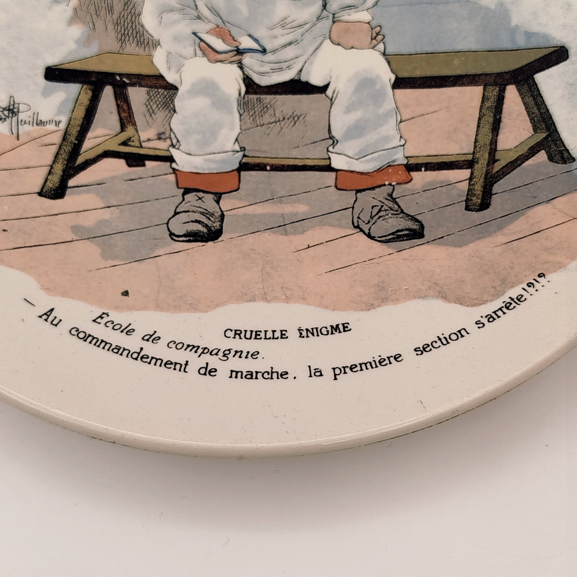 Тарелка декоративная "Cruelle Enigme. Ecole de compagnie.  Au commandement de marche, la premiere section s'arrete!?" ("Жестокая загадка. Школа роты. По команде к маршу первый отряд останавливается!?"), с подписью автора рисунка, фаянс, деколь, Sarreguemines (Саргемин), Франция, 1890-1920 гг.