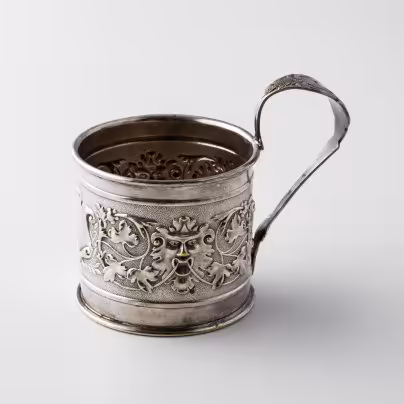 Подстаканник, декорированный виноградными лозами, картушем и маскаронами в виде львов, латунь, серебрение, фабрика "Schiffers&Co", г. Варшава, Польша, 1885-1914 гг.