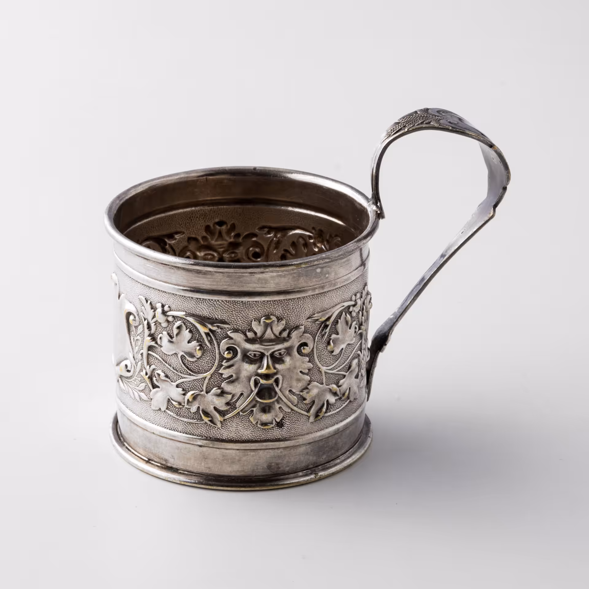 Подстаканник, декорированный виноградными лозами, картушем и маскаронами в виде львов, латунь, серебрение, фабрика "Schiffers&Co", г. Варшава, Польша, 1885-1914 гг.