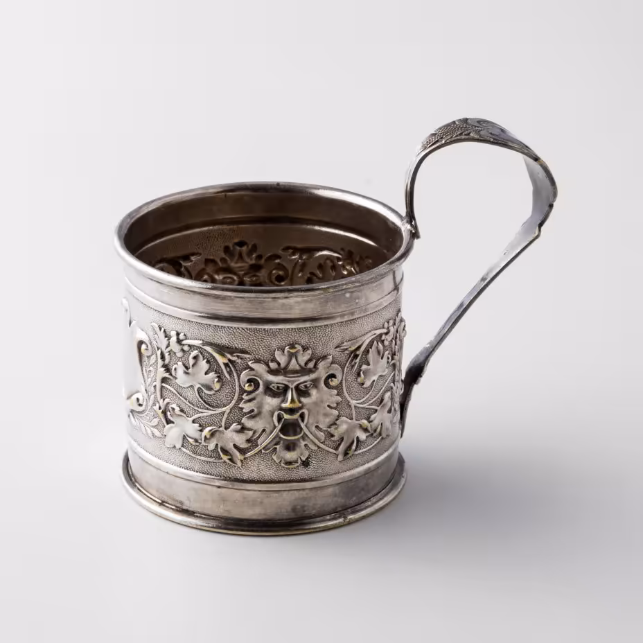 Подстаканник, декорированный виноградными лозами, картушем и маскаронами в виде львов, латунь, серебрение, фабрика "Schiffers&Co", г. Варшава, Польша, 1885-1914 гг.